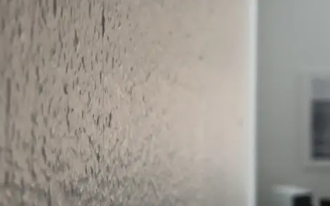 Närbild på en vägg med en grov textur, som om någon har valt att bredspackla strukturtapet för att skapa en unik yta.