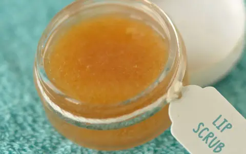 Un tarro de exfoliante de labios casero con etiqueta "Lip Scrub" sobre una toalla turquesa.