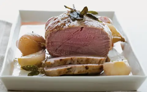Succulento filetto al forno, cotto alla perfezione con cipolle e erbe aromatiche, servito su un piatto bianco.