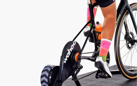Cyclist training indoors on a bike with a Wahoo trainer, experiencing adjustable bike resistance for a challenging workout.