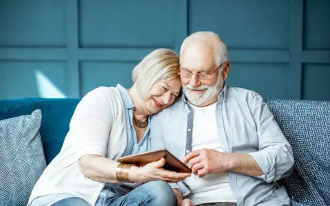 Uśmiechnięta para seniorów przegląda tablet. Szukają informacji: operacja zaćmy NFZ gdzie najszybciej, by odzyskać jasność widzenia.