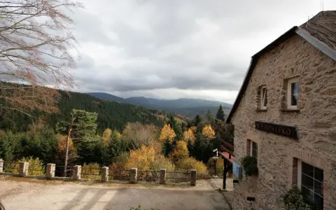 Kamienny budynek schroniska na Iglicznej z widokiem na jesienne góry.