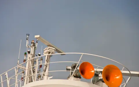 Zwei orangefarbene Schiffshörner sind bereit, ihr Signal zu geben. Das Schiff hupt 3 mal lang, um seine Anwesenheit zu signalisieren.