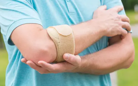 Mann mit Bandage am Ellenbogen, um Schmerzen bei Tennisarm zu lindern.