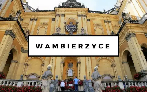Bazylika w Wambierzycach, znana z licznych atrakcji, zachwyca architekturą. Widać schody prowadzące do sanktuarium, ozdobione czerwonymi kwiatami.