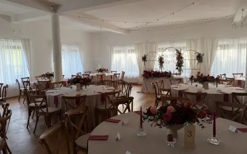 Elegancka sala weselna z okrągłymi stołami, kwiatami i świecami. Idealne miejsce, by wybrać najlepszą salę na wesele.