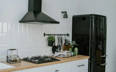 A clean vent hood filter is crucial for kitchen safety and efficiency. This image shows a modern kitchen with a black vent hood over a gas stove.