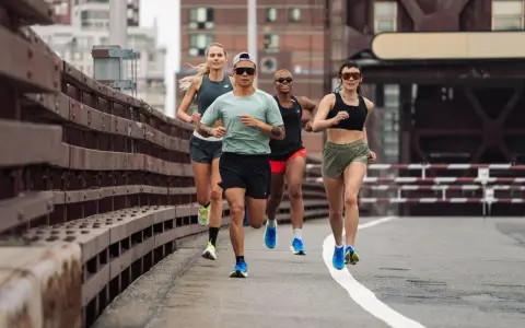 Grupa biegaczy w różnym tempie pokonuje trasę. Intensywny fartlek run na moście miejskim.
