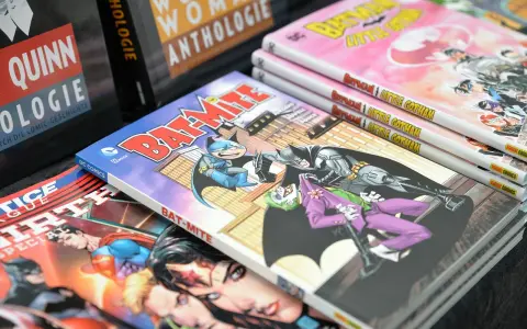 Fumetti DC Comics impilati, tra cui "Bat-Mite" e "Batman Little Gotham". Un lavoro da fumettista che prende vita.