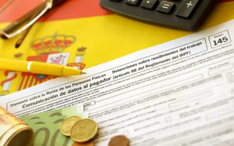 Documentos fiscales españoles, calculadora, bolígrafo amarillo y dinero, listos para cuando se pagan impuestos en España.
