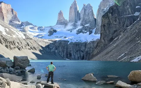 Widok na majestatyczne Torres del Paine w Chile. Turysta podziwia turkusowe jezioro i ośnieżone szczyty.