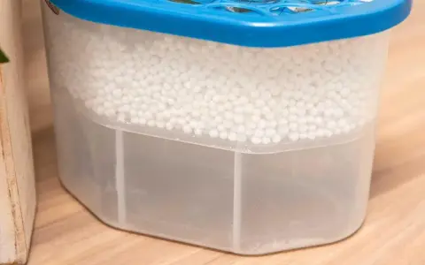 Luftentfeuchter Granulat wird hart, wenn es Feuchtigkeit aufnimmt. Der Behälter zeigt, wie das Granulat die Luft trocknet und sich unten Wasser sammelt.