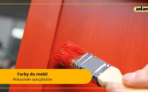 Pędzel z czerwonymi włoskami nakłada farby do malowania na drewnie na pomarańczowe meble.