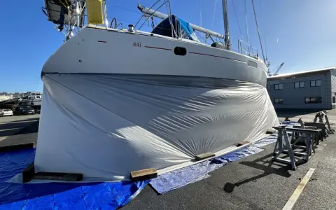Bateau bâché, prêt pour le sablage de sa coque. Le prix du sablage coque bateau est une étape clé pour sa rénovation.