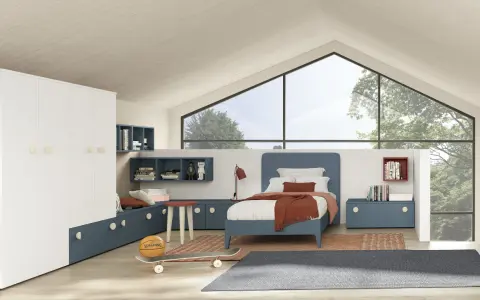 Un accogliente **letto sotto la finestra** in una stanza moderna, con armadio bianco, librerie blu e un pallone da basket.