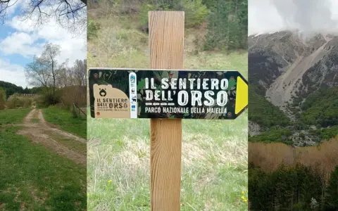 Segnale del sentiero dell'orso nel Parco Nazionale della Maiella, con un sentiero sterrato e montagne sullo sfondo.
