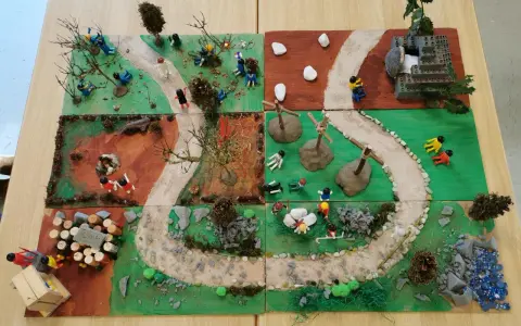Kinder gestalten einen Kreuzweg mit Spielfiguren und Naturmaterialien. Kleine Szenen zeigen Stationen des Leidenswegs.