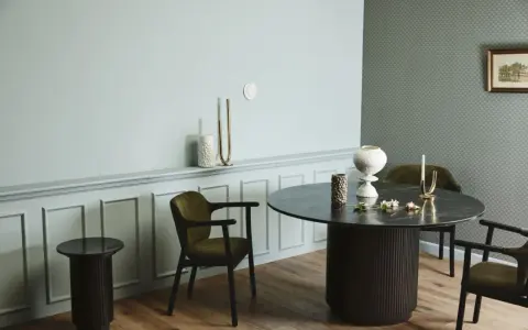 Ett runt matbord med mörka stolar skapar en inbjudande atmosfär. Utrymme runt matbordet ger plats för samtal och gemenskap.