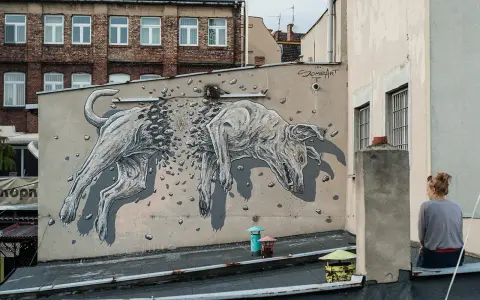 Niesamowite street art graffiti przedstawiające psa rozpadającego się na kamienie. Dzieło sztuki miejskiej na ścianie kamienicy.
