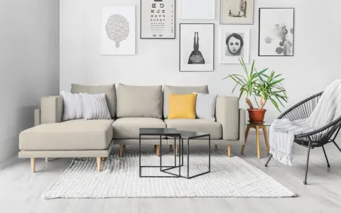 Divano componibile beige con cuscini, tavolini neri, tappeto bianco e sedia nera. Ispirazione per come foderare un divano fai da te.