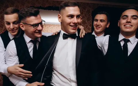 Uśmiechnięci panowie w garniturach, przygotowujący się na ekstremalny wieczór kawalerski.