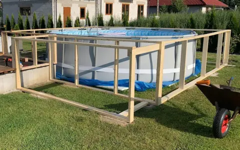 Drewniana konstrukcja wokół basenu ogrodowego w trakcie budowy.