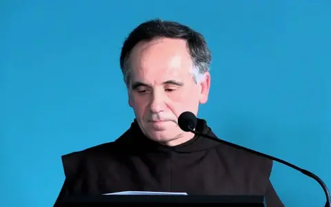 Mężczyzna w habicie przed mikrofonem, czytający psalm 140 tekst.