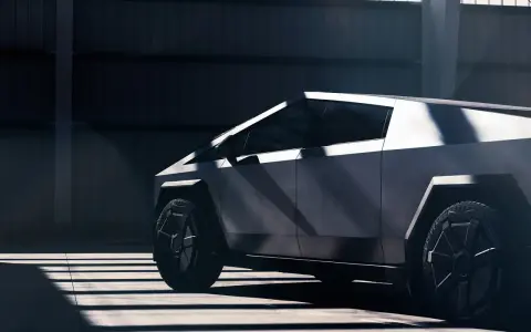 Tesla Cybertruck w ciemnym wnętrzu, widok z boku, podkreślony przez światło i cień.