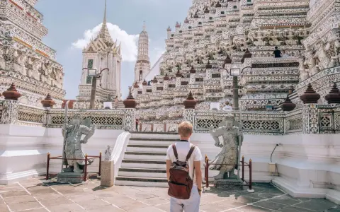 Młody turysta z plecakiem podziwia majestatyczną świątynię Wat Arun w Bangkoku. Czy Bangkok jest bezpieczny? Tak, zwłaszcza w takich pięknych i spokojnych miejscach.