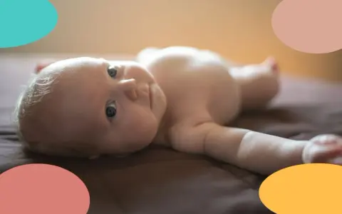 Un bebé de 2 meses, con ojos curiosos, yace boca arriba. Parece que este pequeño no duerme, ¡sus ojitos están bien abiertos!
