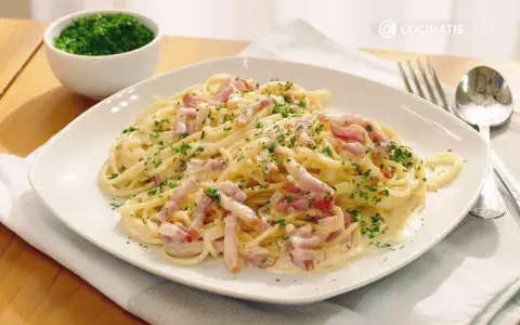 Espaguetis con nata, cubiertos de trocitos de bacon y perejil picado. Un plato cremoso y delicioso.