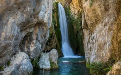 Cascada cayendo en pozas cristalinas, un rincón idílico de piscinas naturales Alicante.