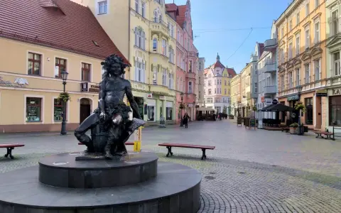 Fontanna z postacią Baccha na brukowanym placu, otoczona kolorowymi kamienicami. Zielona Góra atrakcje turystyczne.
