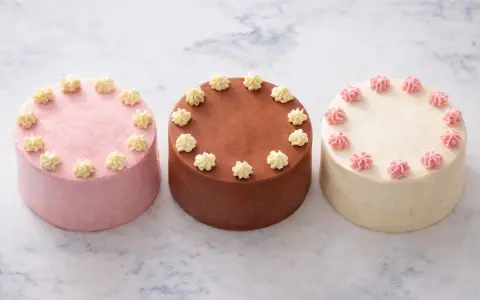 Trois petits gâteaux décorés, parfaits pour une recette de bento cake. Un rose, un chocolat, un vanille.