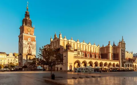 Rynek Główny w Krakowie, idealne miejsce na city break. Sukiennice i wieża Ratuszowa w słońcu.