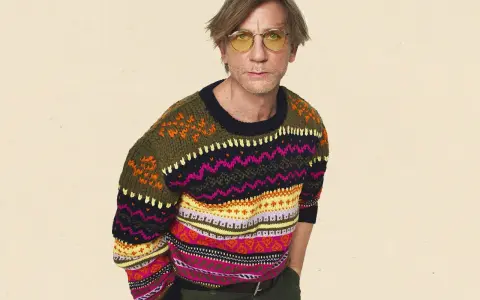 Mann mit gelber Brille trägt einen bunten Pullover aus Wolle, schleudern von Mustern.