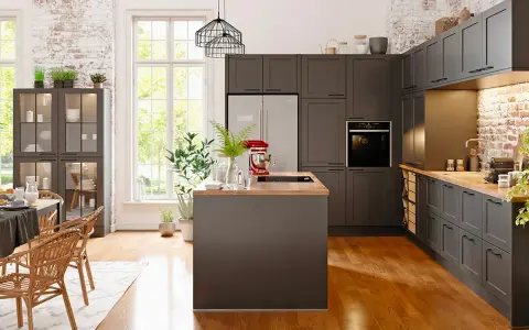 Cuisine moderne avec îlot central et armoires sombres. Un réfrigérateur non encastrable est discrètement intégré dans le décor.