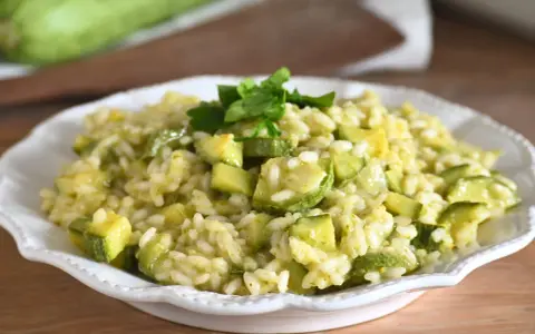 Un cremoso risotto con zucchine, guarnito con prezzemolo fresco, pronto per essere gustato.