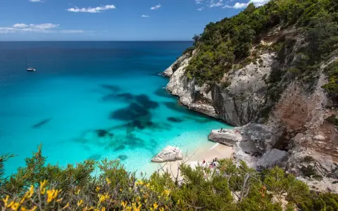 Traumhafter Strand Sardinien mit türkisfarbenem Wasser, Felsen und grüner Vegetation. Eine kleine Bucht lädt zum Entspannen ein.