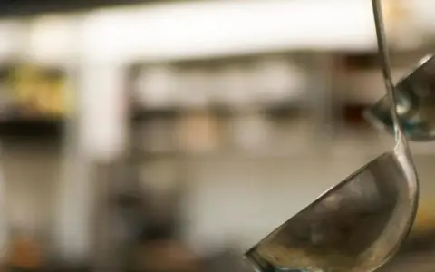 Deux louches en métal suspendues dans une cuisine. L'une est au premier plan, l'autre est floue en arrière-plan.