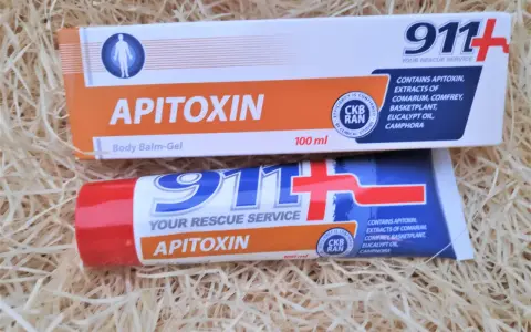 Dwa opakowania kremu z jadem pszczelim "Apitoxin" 911+ na tle słomy.
