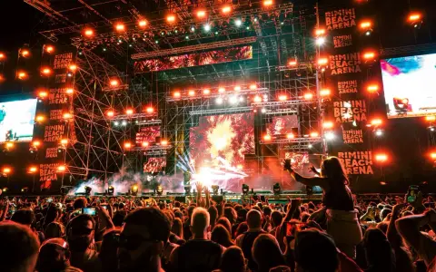Un concerto elettrizzante alla Rimini Beach Arena. Migliaia di fan in delirio sotto un palco imponente illuminato da luci stroboscopiche e schermi giganti.