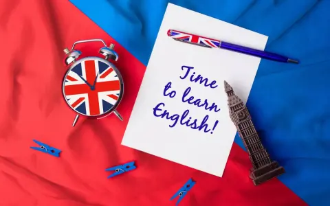 Budzik z flagą UK, długopis i napis "Time to learn English!" na tle brytyjskich barw. Czas na naukę!