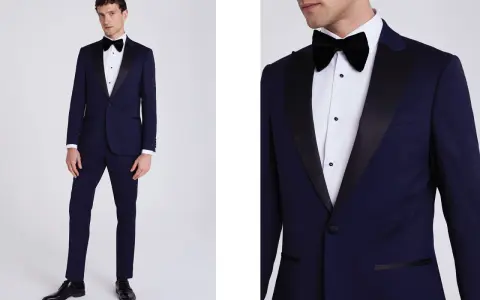 A man models a navy tuxedo with black satin lapels. Inquire about how much are tuxedos rentals for your next formal event.