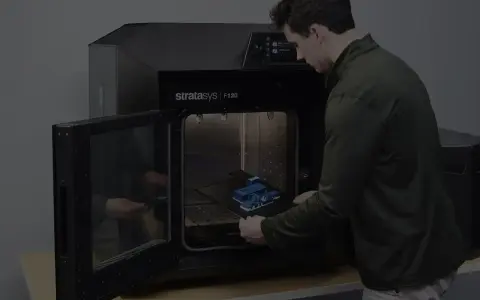 Mężczyzna wkłada wydrukowany model do drukarki 3D Stratasys F120. Tak wygląda drukarka 3d w akcji.