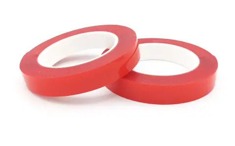 Zwei Rollen rotes Schaumklebeband liegen nebeneinander auf weißem Hintergrund.
