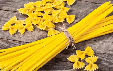 Makaron z mąki durum i zwykłej pszennej. Farfalle i spaghetti na drewnianym tle.