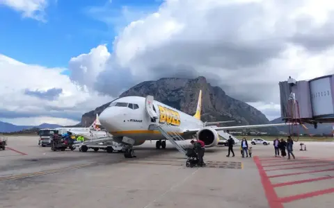 Samolot Buzz by Ryanair na lotnisku na Sycylii, z górami w tle.