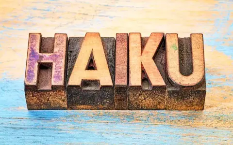 Träbokstäver bildar ordet "HAIKU" på en sliten träyta. En hyllning till den korta, poetiska formen.