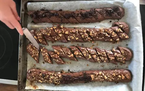 Chokladsnittar recept: Nybakade chokladkakor med nötter och chokladbitar skärs upp på en plåt.